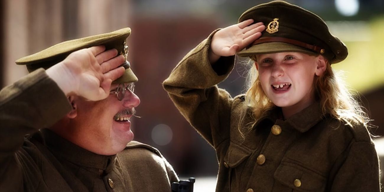 A smiling man and child salute each other while dressed as soldiers