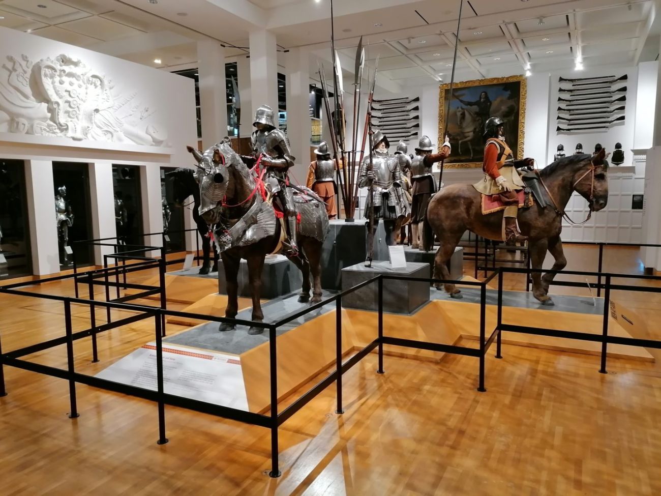 Horses with armour and men wearing armour in a museum gallery