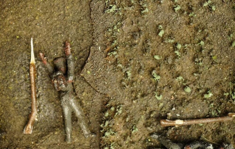 A body lies in a field filled with weeds and mud