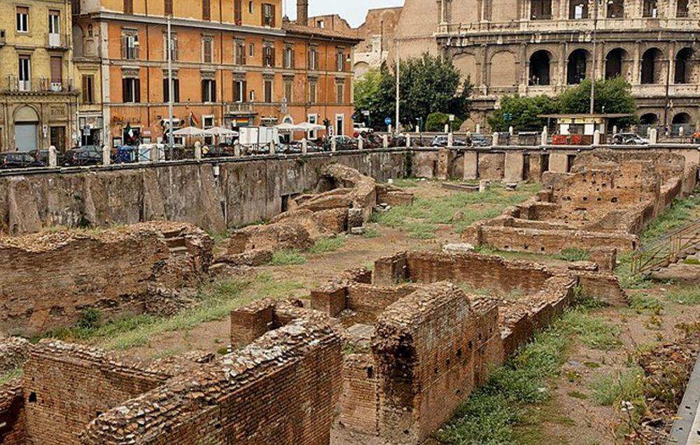 The uncovered ruins of the Ludus Magnus in Rome, next to the Colosseum in the background