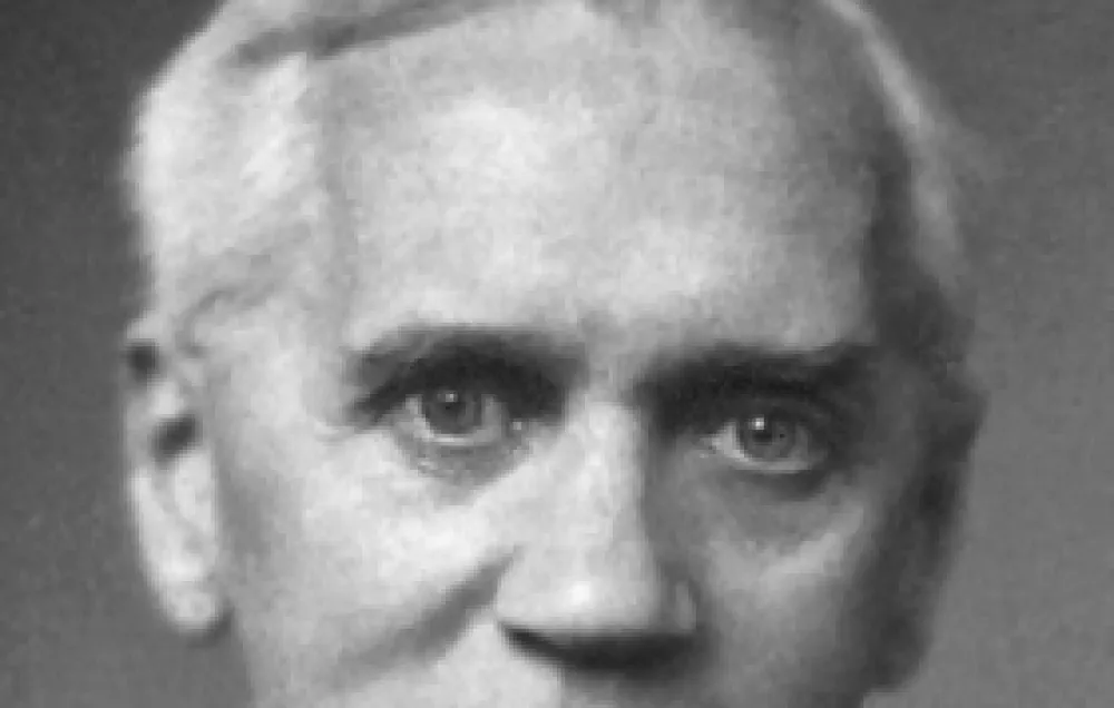 A black and white photograph of Alexander Fleming, with white hair and a bow tie