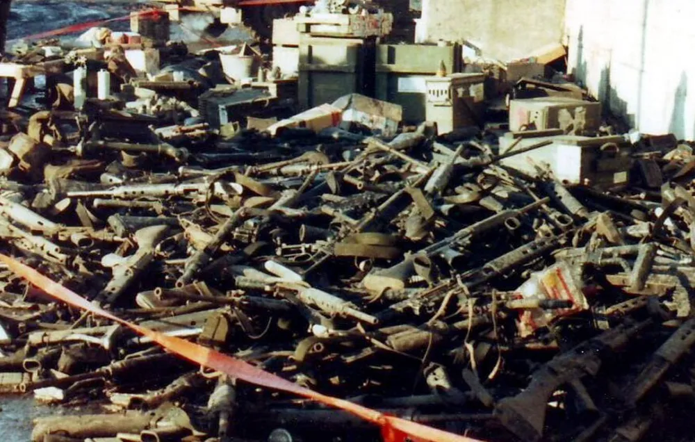 A colour photograph of a large pile of discarded weapons left by Argentine conscripts after the recapture of the Falklands