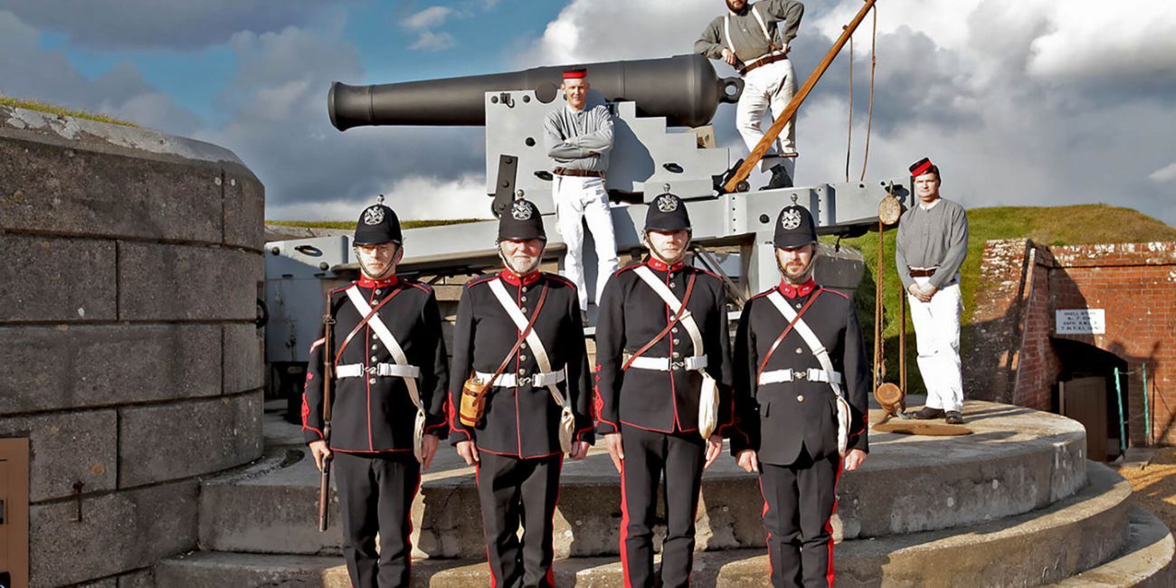 Seven men in Victorian military uniform manning a large cannon on the Fort's ramparts