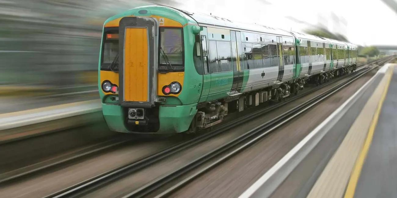 a green and yellow train speeding through a station