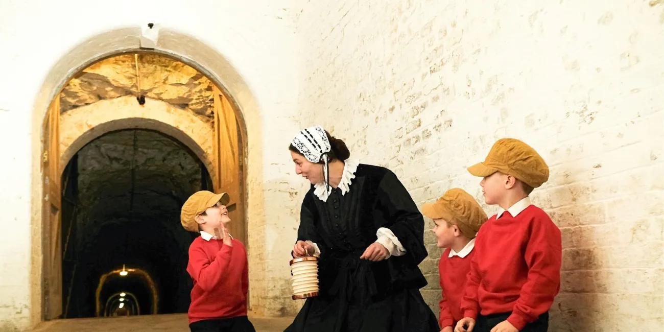 Florence Nightingale kneels on a bloodstained sheet with school children kneeling beside her