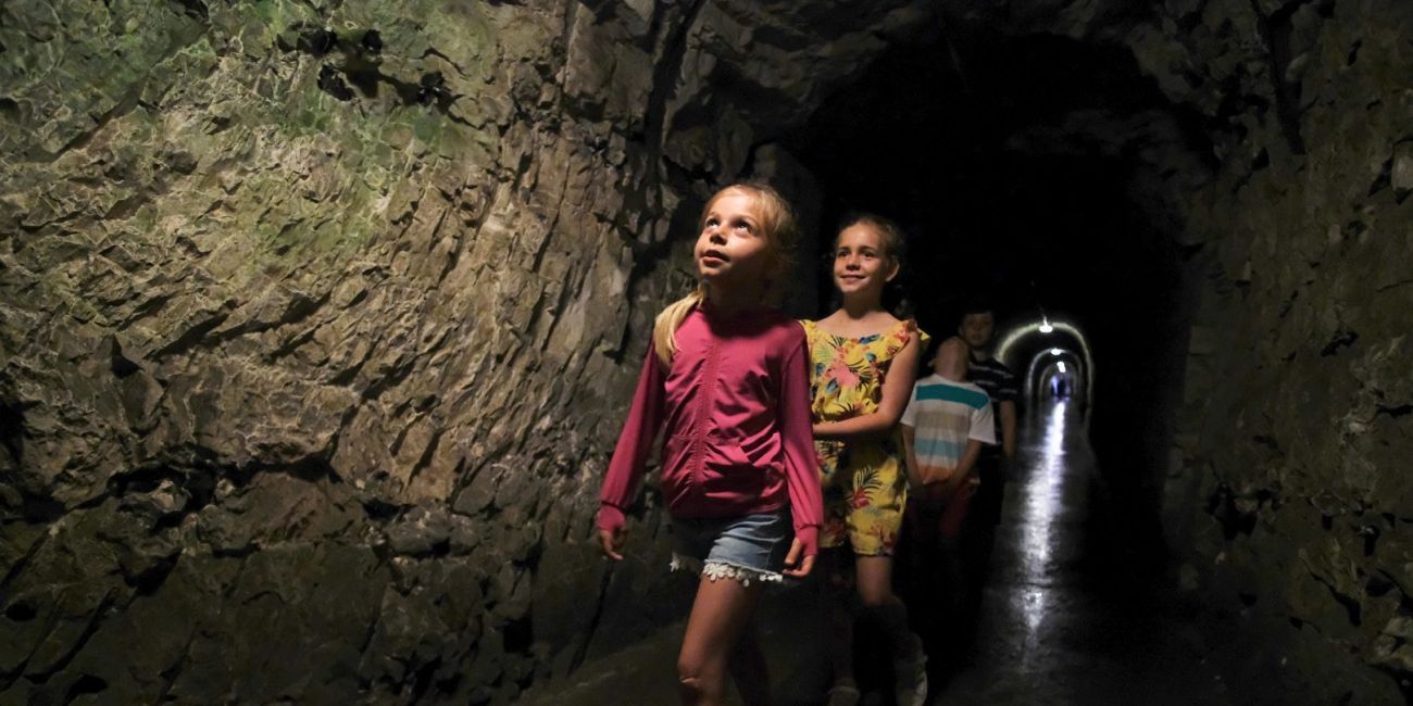four children walking through a dimly lit underground tunnel