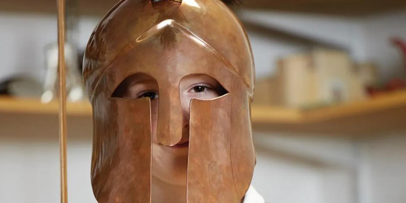 Schoolboy wearing bronze helmet and breastplate