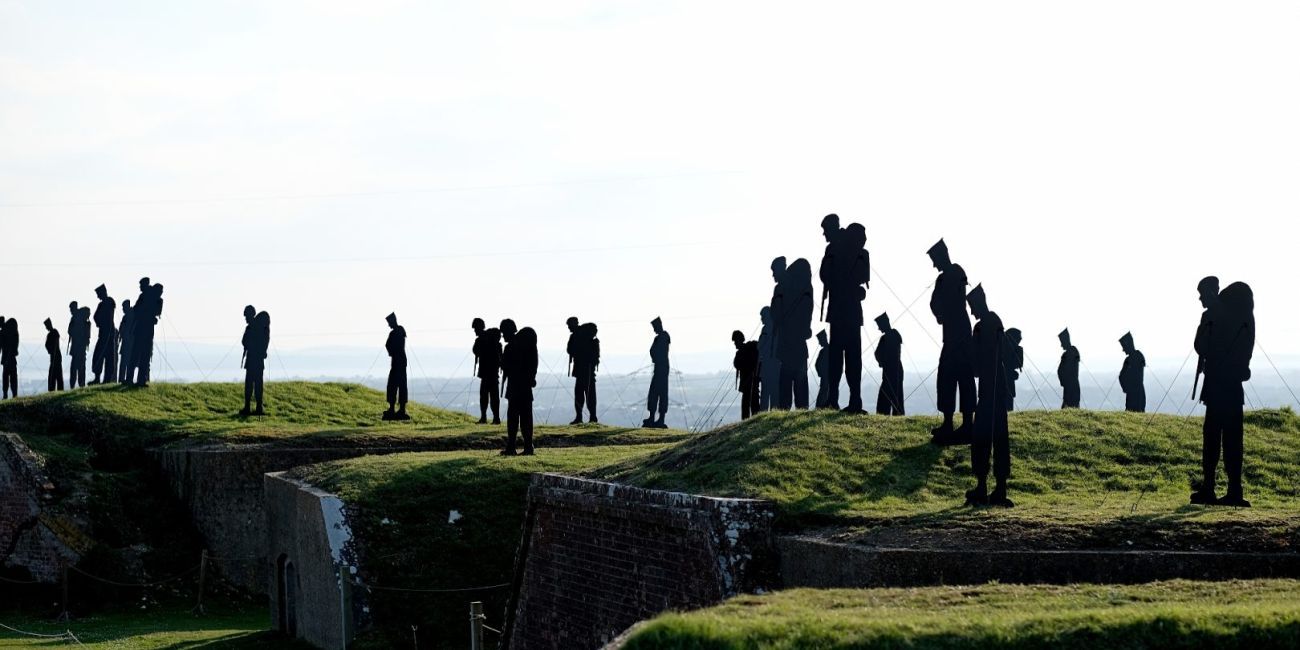 Giant Silhouettes of Falkland service men standing on top of grass ramparts