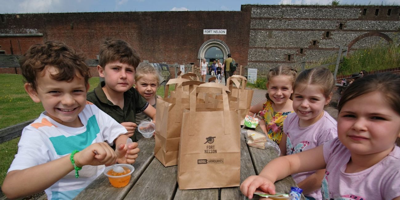 group of 6 children sitting at a bench eating snacks