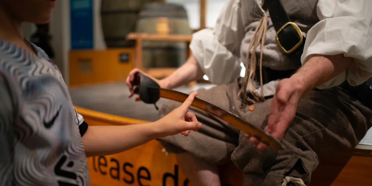After the show a child curiously feels the edge of the interpreter's sword blade