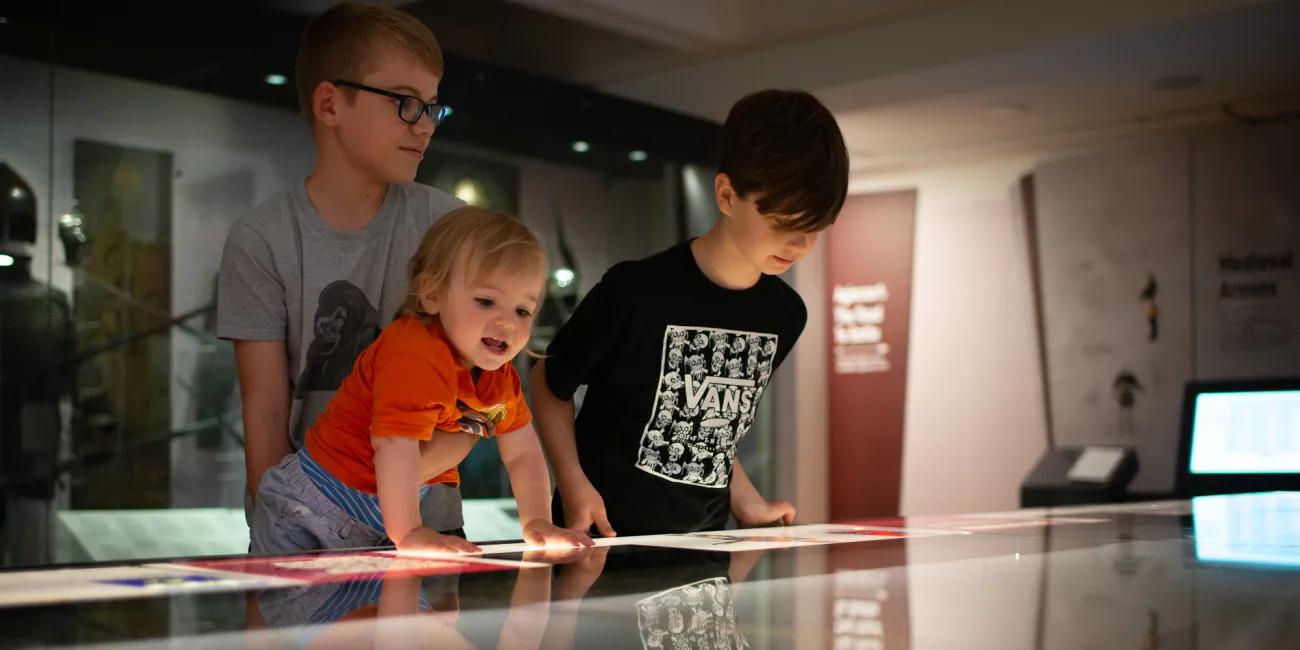 three excited children getting a better look at the Agincourt model