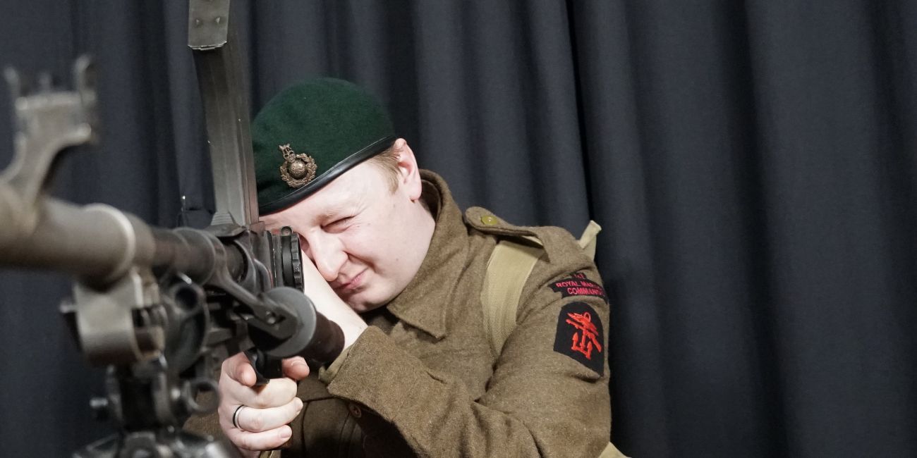 Second World War soldier in uniform looks down the barrel of a gun