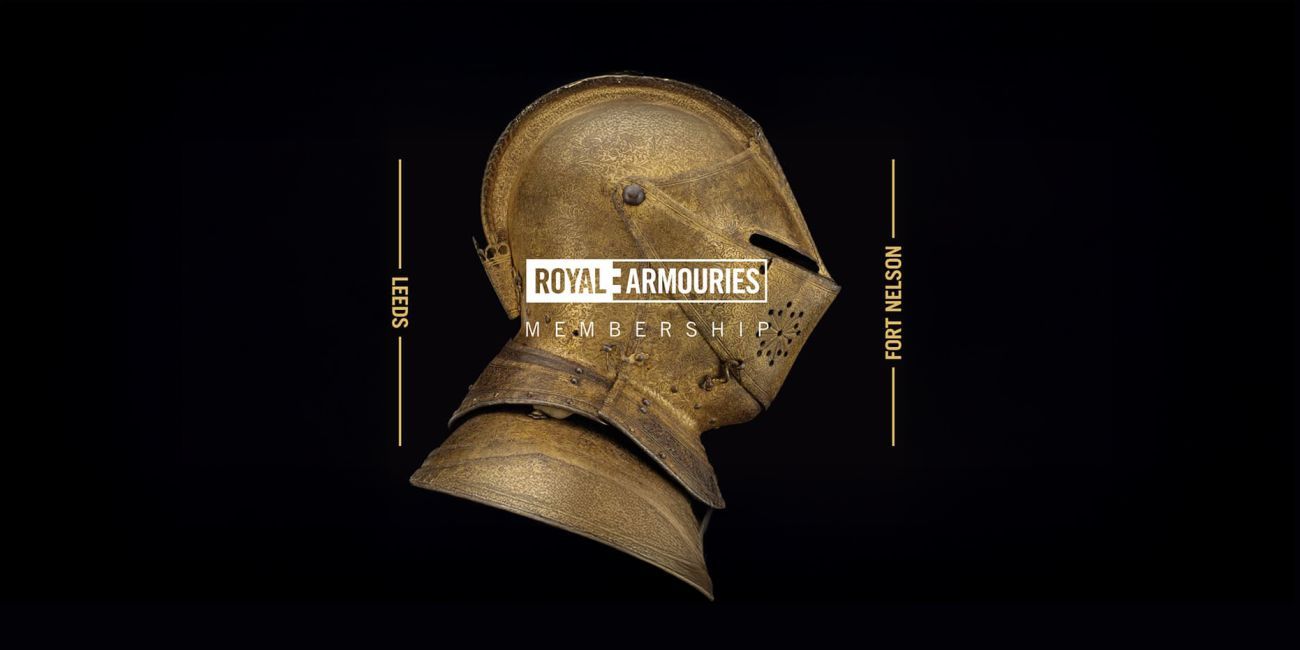 Gold coloured highly decorated armoured helmet with visor down on a black background