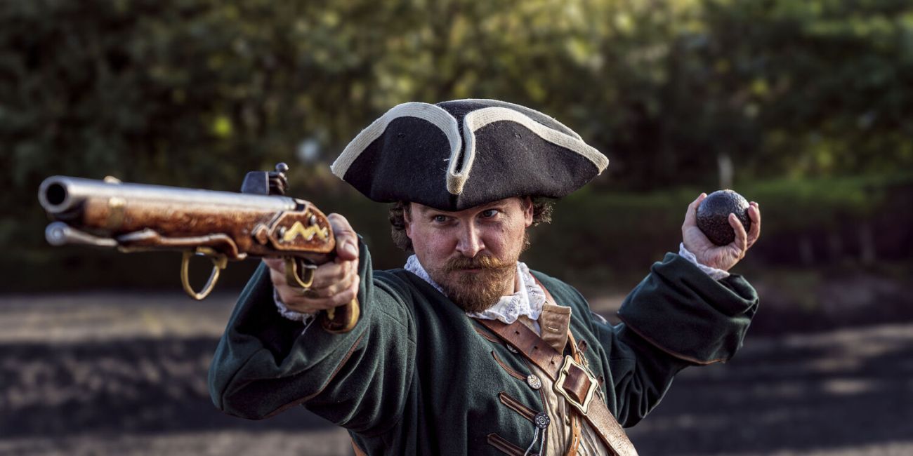 Pirate aiming musket in one hand and holding grenade in the other