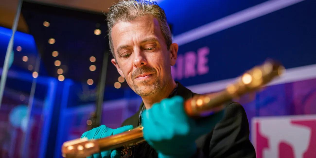 Jonathan Ferguson holding gold AK47 for RE:Loaded exhibition launch 