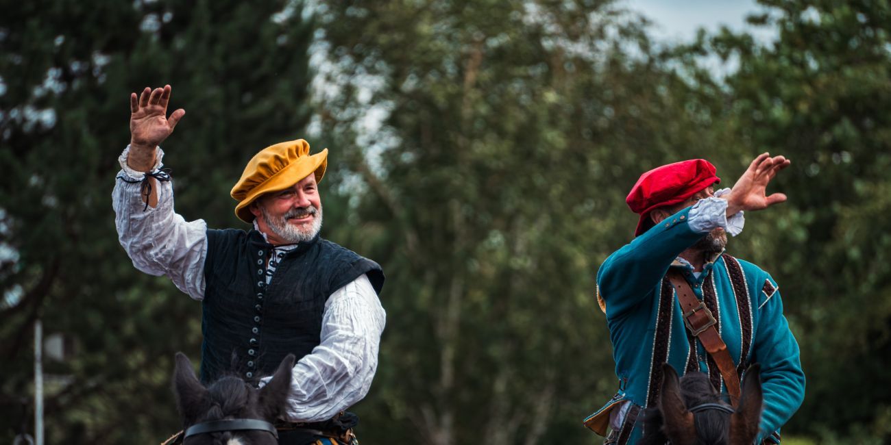Two jousters on horseback waving at crowd