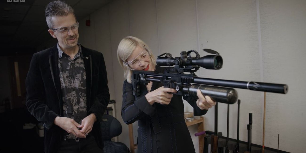 Lucy Worsley aiming a firearm stood next to Jonathan Ferguson