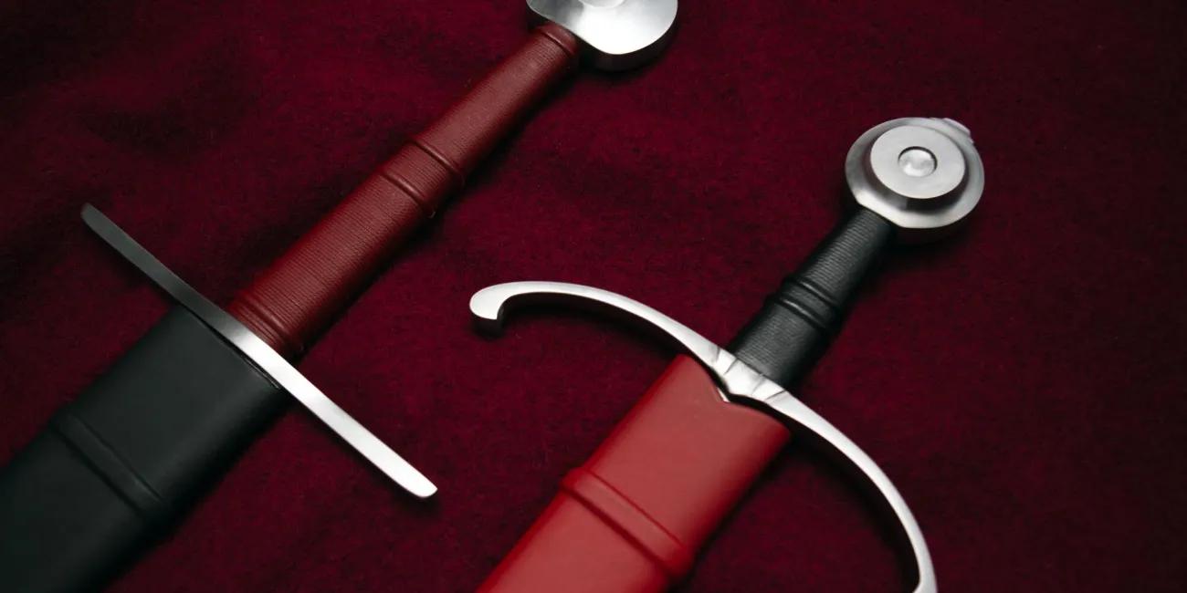 Two sword hilts side by side on red fabric