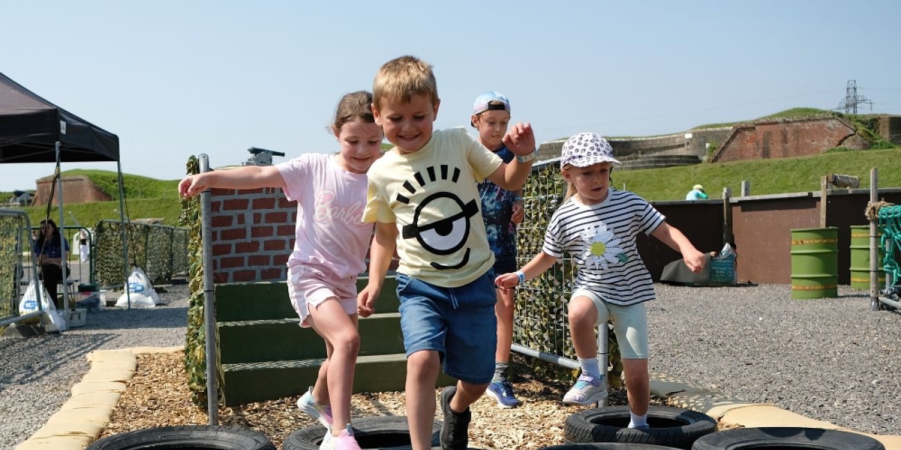 Four children walking across tyres laid flat