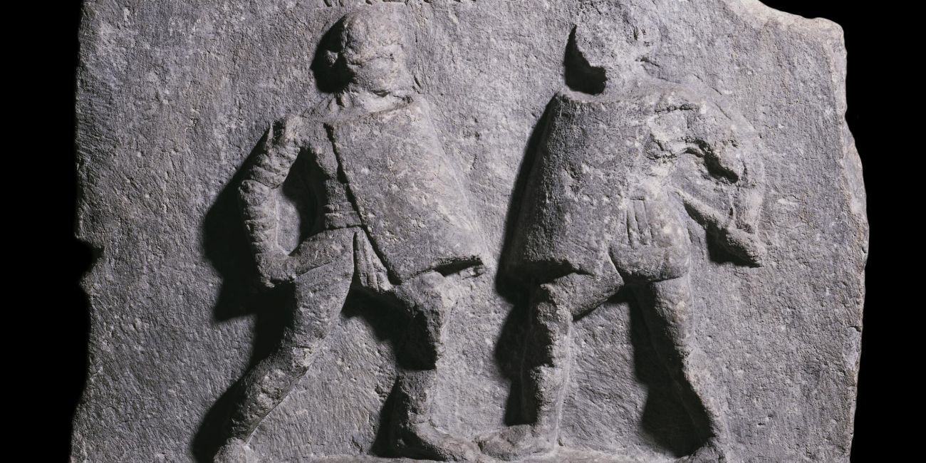 Stone carved with two figures with swords and shields