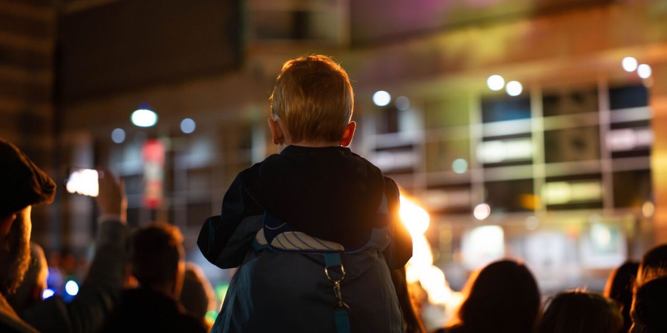 Child on adults shoulders watching performance