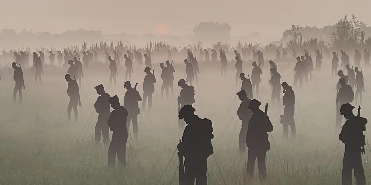 100s of life-sized silhouettes representing soldiers, in a field at dawn with mist on the ground
