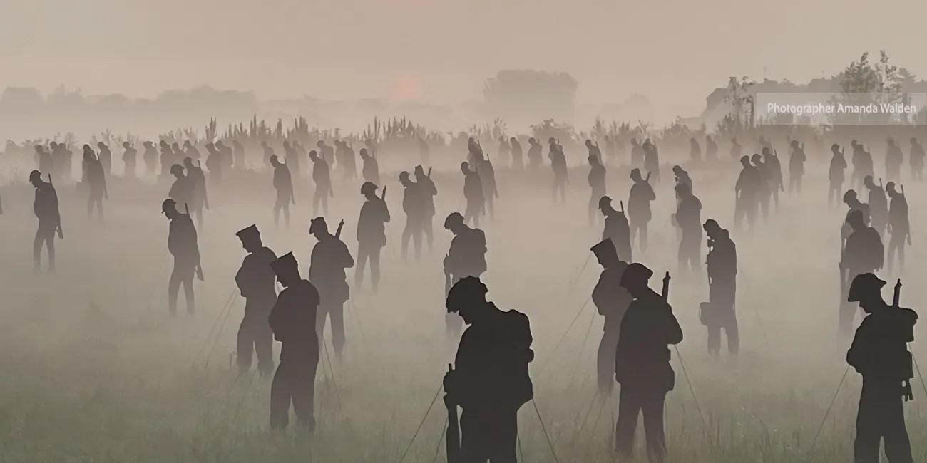 100s of life-sized silhouettes representing soldiers, in a field at dawn with mist on the ground - photographer Amanda Walden