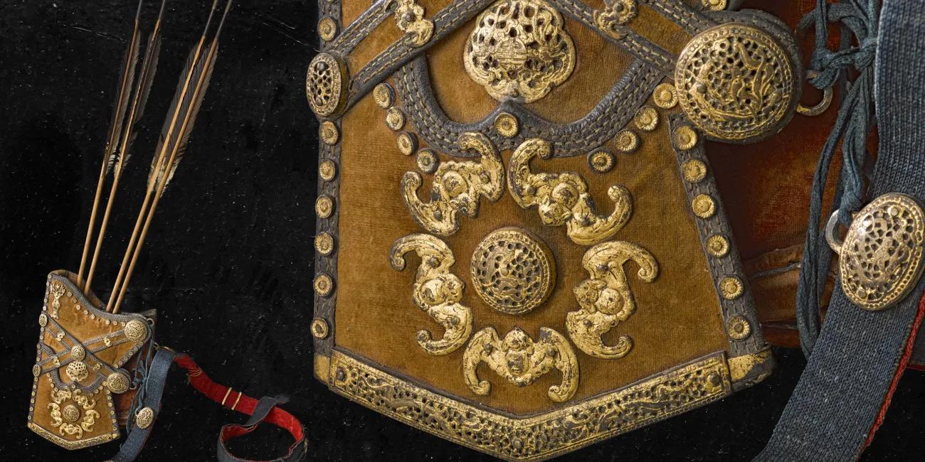 Detailed view of a richly adorned bow case with gilded metalwork and a quiver containing arrows, showcasing elaborate craftsmanship and decorative motifs