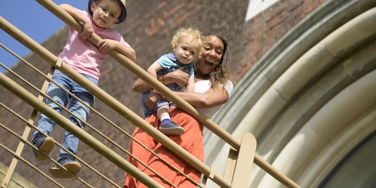 Woman and 2 young children looking over bridge
