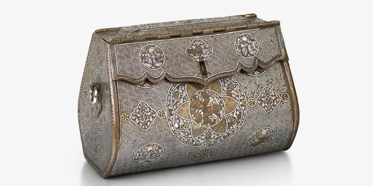 Decoratively engraved bag with a domed hinged lid, detailed surface ornamentation, and a prominent circular design on the front face.