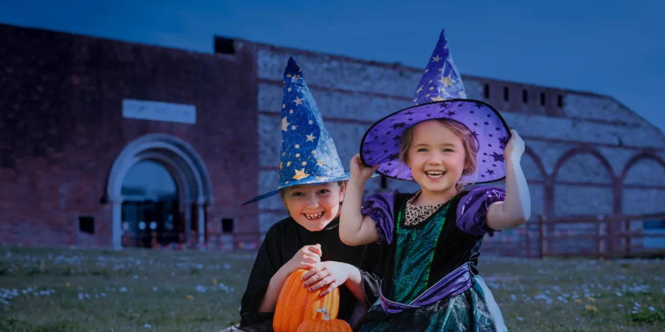 Two girls dressed as witches in front of Fort Nelson