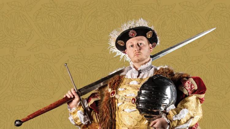 Man dressed in period Tudor costume with sword resting on his right shoulder and a knights helmet in his left hand