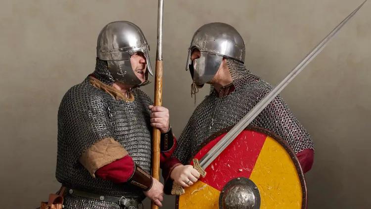 Two Viking and Saxon warriors in mail armour and helmets face off with spear, sword and shield