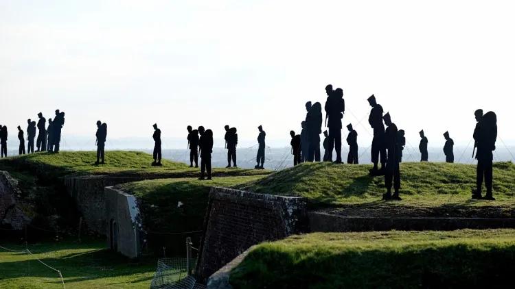 Giant Silhouettes of Falkland service men standing on top of grass ramparts