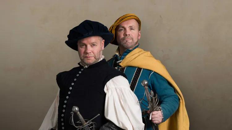 wo flamboyantly dressed Renaissance sword masters posing with their swords