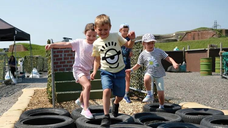 Four children walking across tyres laid flat
