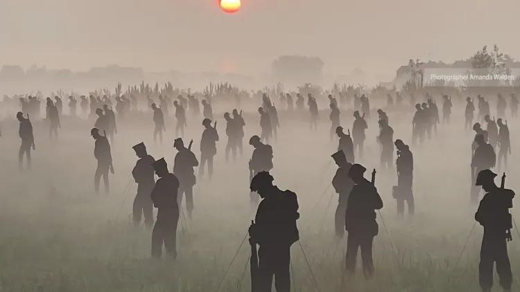 100s of life-sized silhouettes representing soldiers, in a field at dawn with mist on the ground - photographer Amanda Walden