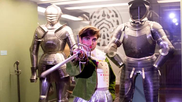 Person with sword standing between two suits of armour