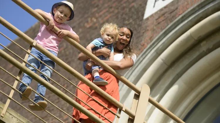 Woman and 2 young children looking over bridge