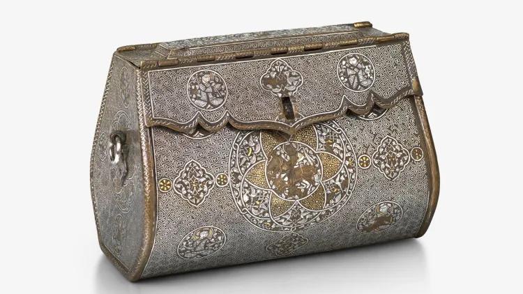 Decoratively engraved bag with a domed hinged lid, detailed surface ornamentation, and a prominent circular design on the front face.