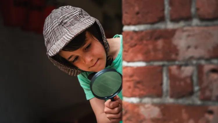 Child in hat with magnifying glass