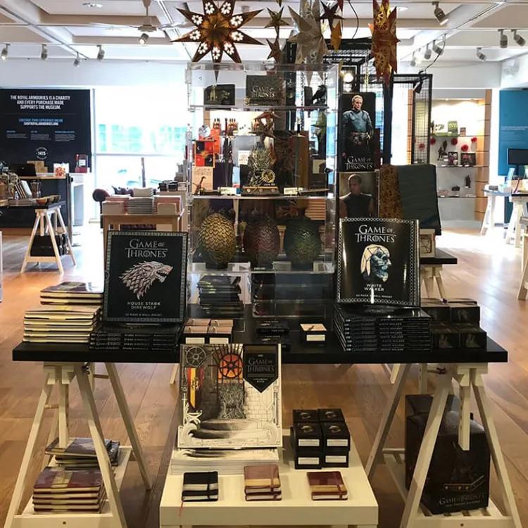 the inside of a shop with books in foreground and swords in the background