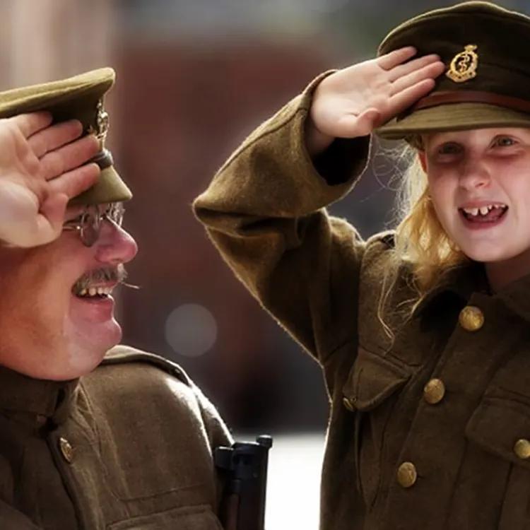 A smiling man and child salute each other while dressed as soldiers