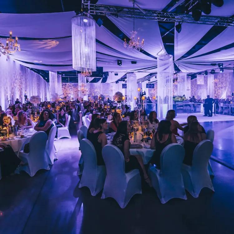 people sat at round tables at an event in a beautifully decorated venue