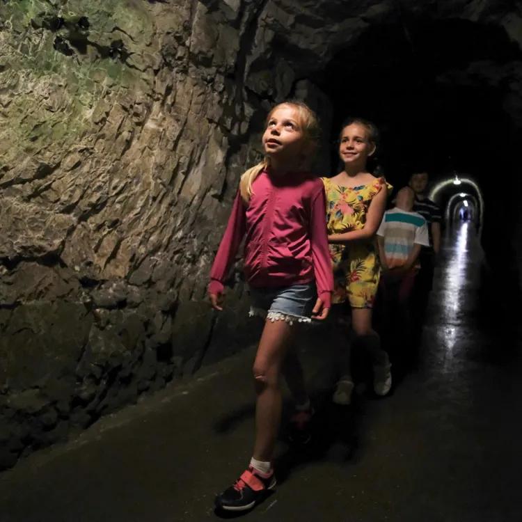 four children walking through a dimly lit underground tunnel