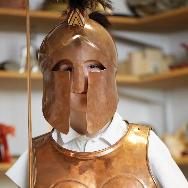 Schoolboy wearing bronze helmet and breastplate