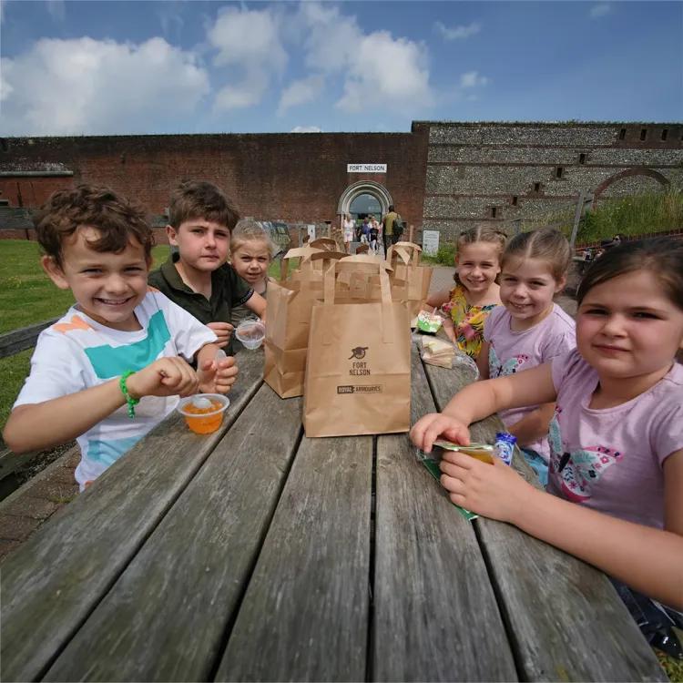group of 6 children sitting at a bench eating snacks