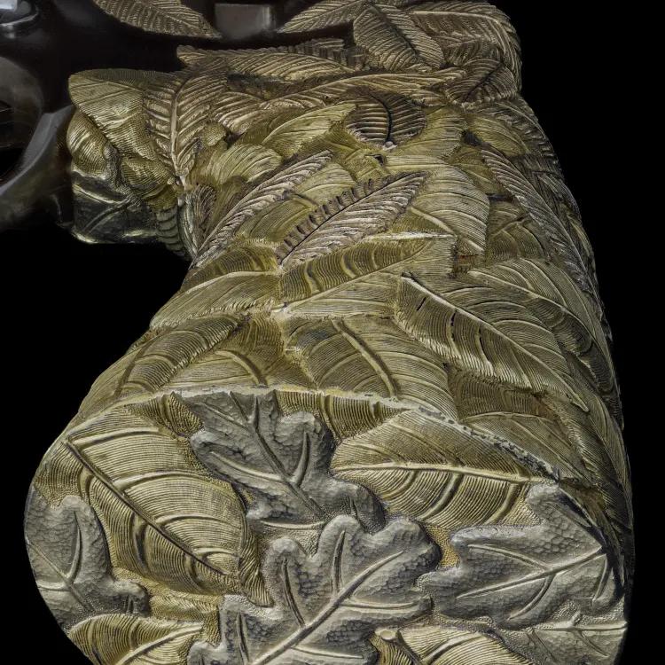 A close up of a revolver stock decorated in gold leaf on a black background