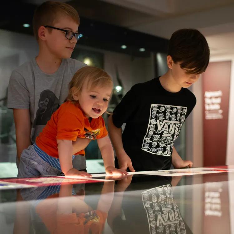 three excited children getting a better look at the Agincourt model