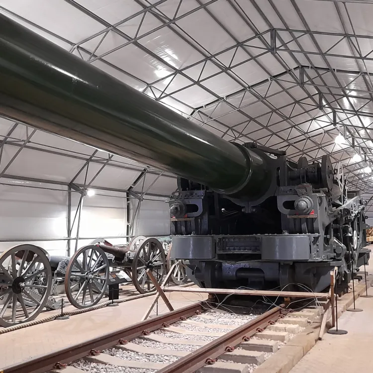 A railway carriage mounted cannon in green in a grey hanger